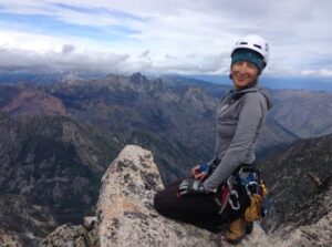Woman kneeling on rock on the summit of a mountain.